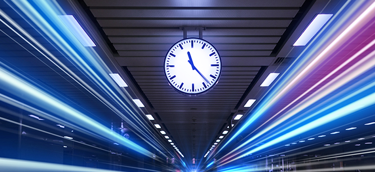 Clock in train station showing long exposure blurred trains, to indicate speed